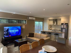 a living room with a couch and a tv and a kitchen at Cowes Luxury Getaway in Cowes
