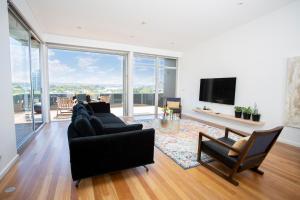 a living room with black furniture and a large window at Sydney Penthouse in Sydney