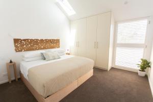 een witte slaapkamer met een groot bed en een raam bij Sydney Penthouse in Sydney