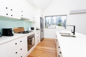 una cucina con banconi bianchi e una grande finestra di Sydney Penthouse a Sydney