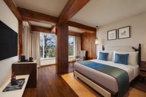 a bedroom with a large bed with blue pillows at jüSTa Hollow Oak, Mussoorie in Mussoorie