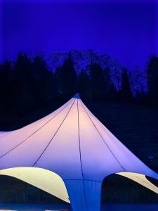 Une grande tente blanche est éclairée la nuit. dans l'établissement Zhangjiajie National Forest Park Camping, à Zhangjiajie