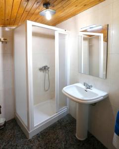 a white bathroom with a shower and a sink at A casa do pozo - AS CASAS DO POZO - in Folgoso