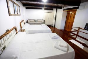 two beds in a room with white sheets at A casa do pozo - AS CASAS DO POZO - in Folgoso