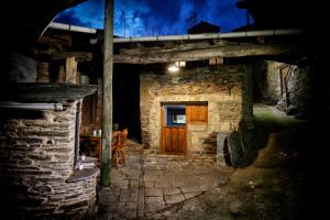 a stone house with a wooden door and a table at A CASA DO POZO in Folgoso