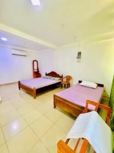 Habitación con 2 camas y 2 sillas en Touch Down Family Restaurant & hotel en Katunayaka