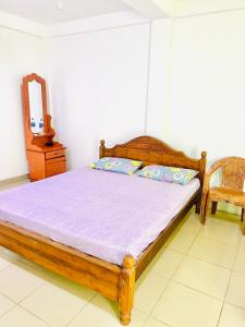 1 dormitorio con cama de madera y espejo en Touch Down Family Restaurant & hotel en Katunayaka