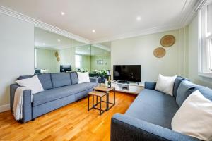 Sala de estar con 2 sofás azules y TV en Location Trafalgar Square 1 Bedr, 3 Beds, sleeps 6, en Londres