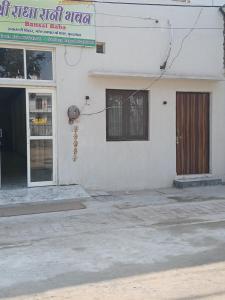 ein weißes Gebäude mit einer Tür und einem Fenster in der Unterkunft Shri Radha Rani Bhawan in Vrindāvan