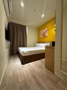 1 dormitorio con 1 cama con pared amarilla en SGI Vacation Club Hotel en Melaka