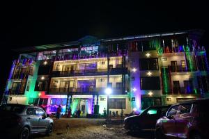 een verlicht gebouw met auto's voor het gebouw bij HOTEL AKSHAYAM GRAND INN in Yelagiri