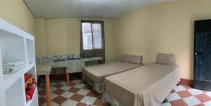 a bedroom with two beds and a table and a window at CASA BATZ #1 in San Pedro La Laguna