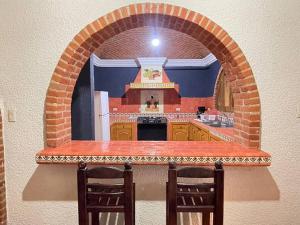 a kitchen with an arch shaped counter with two chairs at Casa Orquidea in San Miguel de Allende +13 photos