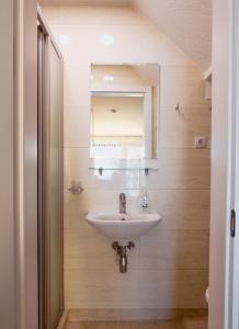 ein Bad mit einem Waschbecken und einem Spiegel in der Unterkunft Curonian apartments in Nida