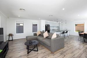 a living room with a gray couch and a kitchen at Stylish Urban Getaway in the Heart of the City in Wagga Wagga