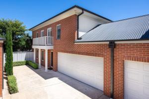 a brick house with two white garage doors at Stylish Urban Getaway in the Heart of the City in Wagga Wagga