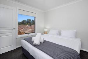 a white bedroom with a large bed and a window at Stylish Urban Getaway in the Heart of the City in Wagga Wagga
