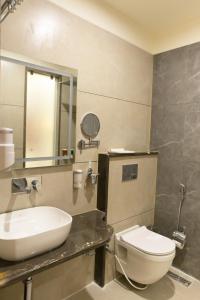 La salle de bains est pourvue d'un lavabo, de toilettes et d'un miroir. dans l'établissement Hotel Aditya Grand, à Bhopal