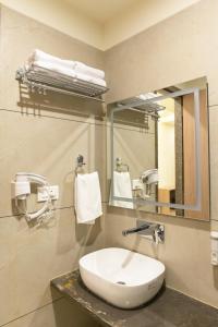 La salle de bains est pourvue d'un lavabo et d'un miroir. dans l'établissement Hotel Aditya Grand, à Bhopal