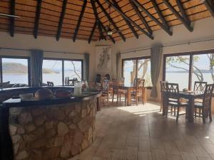 a dining room with tables and chairs and windows at Masumu River Lodge in Binga