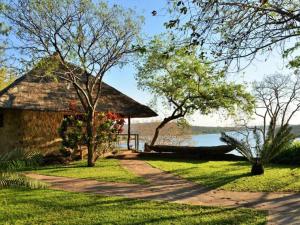 Binga的住宿－Masumu River Lodge，一条通往一座有湖泊背景的建筑的道路