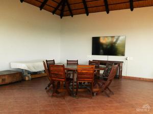 a dining room with a table and chairs and a flat screen tv at Masumu River Lodge in Binga