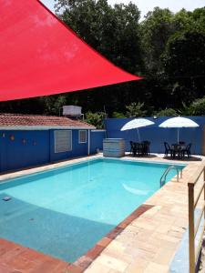 una piscina con techo rojo, mesas y sombrillas en Pousada Albergue Kafundó, en Jaguariúna