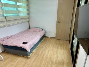 a small bed in a room with a window at Fullhouse 6TO10 in Gangneung