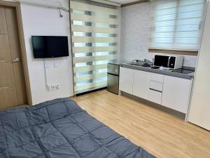 Habitación pequeña con cama y cocina en Fullhouse 6TO10, en Gangneung