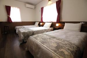 a hotel room with two beds and two windows at Sea Breeze Sumuide 沖縄 in Nago