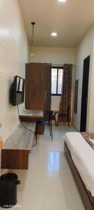 a bedroom with a bed and a desk and a tv at Royal Suites in Pune