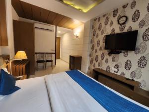 a bedroom with a bed and a flat screen tv at Hotel Arina Inn in New Delhi