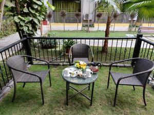 Dos sillas y una mesa con tazas y flores. en Kyriad Prestige Calangute Goa by OTHPL en Calangute