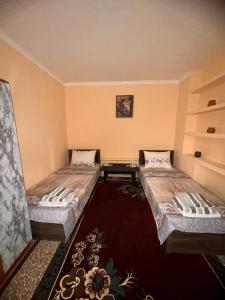 a room with two beds and a table in it at СОФЬЯ ГОСТЕВОЙ ДОМ in Bukhara
