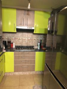 une cuisine avec des armoires vertes et jaunes et une cuisinière dans l'établissement Tu espacio Re - Cuarto descanso, à Santiago