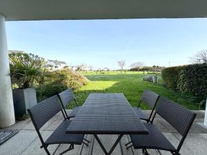 una mesa negra y sillas en un patio en Bel appartement face à la mer - Terrasse et jardin, en Larmor-Plage