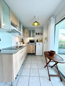cocina con mesa y nevera en Bel appartement face à la mer - Terrasse et jardin, en Larmor-Plage
