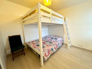 1 dormitorio con litera y silla en Bel appartement face à la mer - Terrasse et jardin, en Larmor-Plage