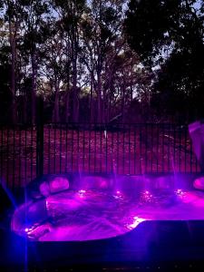 a hot tub with purple lights in front of a fence at Jarrah Glen Cabins in Nannup