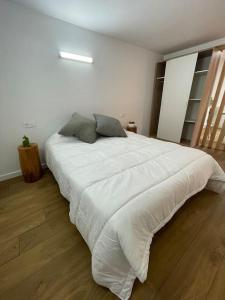 a large white bed in a bedroom with a wooden floor at Apartamento Casa Cesárea in Cedeira