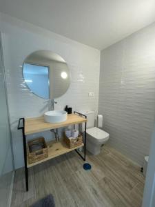a bathroom with a sink and a mirror and a toilet at Apartamento Casa Cesárea in Cedeira