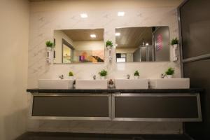 een badkamer met 3 wastafels en een spiegel bij Hostells in Pune +20 foto's