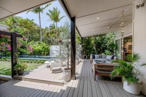 a porch of a house with a couch and chairs at Villa Ohana Pono Luxury Family Home in Sunshine in Sunshine Beach