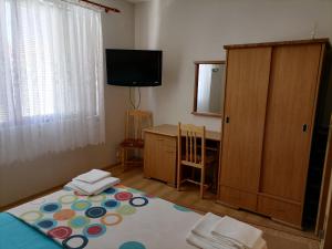 a room with a bed and a dresser and a television at Guesthouse Olimp in Sozopol
