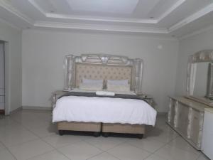 a bedroom with a large bed in a white room at Rest Camp Lodge in Manzini