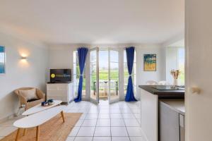 een keuken en een woonkamer met blauwe gordijnen bij Les Maisons de Port Bourgenay - maeva Home - Maison 4 pièces 8 personnes - 291 in Talmont