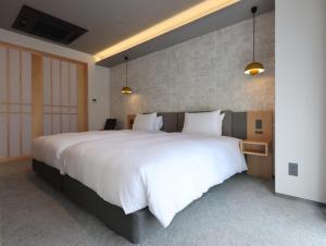 sypialnia z dużym łóżkiem z białą pościelą i poduszkami w obiekcie HOTEL Tomiya with M's w mieście Kioto