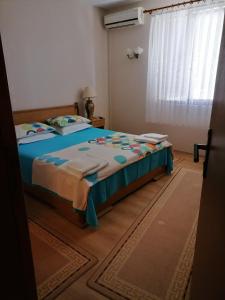 a bedroom with a bed with blue sheets and a window at Guesthouse Olimp in Sozopol