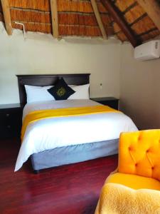 ein Schlafzimmer mit einem großen Bett und einem gelben Stuhl in der Unterkunft GEORGE B BOUTIQUE LODGE in Tzaneen