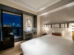 een slaapkamer met een bed, een bureau en een raam bij KOKO HOTEL Premier Nihonbashi Hamacho in Tokyo